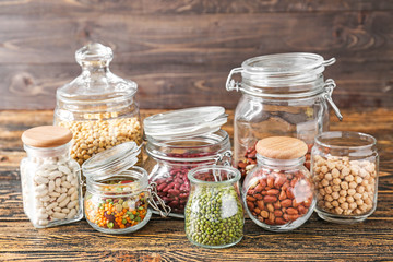 Jars with assortment of legumes on wooden table