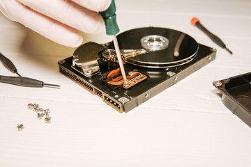 Man repairing hard disk. Inside details of the old personal computer. Broken PC.  Screwdriver in...