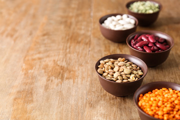 Obraz na płótnie Canvas Bowls with different legumes on wooden background