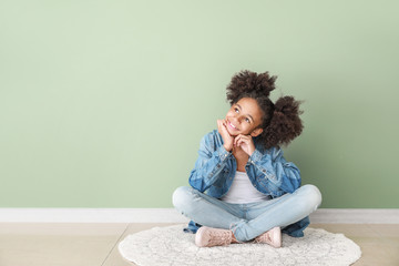 Stylish African-American girl in jeans clothes near color wall