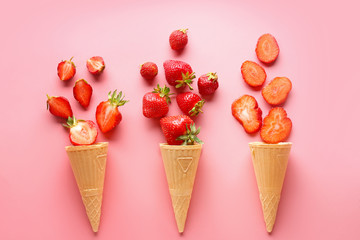 Waffle cones with ripe red strawberry on color background