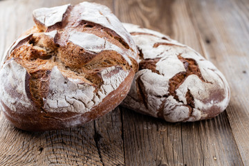 Gold rustic crusty loaves of bread and buns on wooden background. Still life captured from above top view, flat lay.