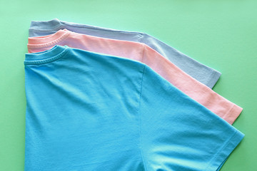 Different t-shirts on color background
