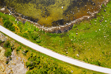 Top down aerial of island grass shoreline littered with boulders. A country road cuts through the landscape. Location Blekinge in Sweden.