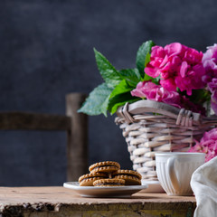 Fototapeta na wymiar Still-life in the rustic style with cookies and hortensia flower in basket on wooden table.