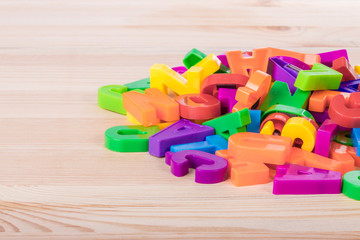 Naklejka premium A pile of coloured magnetic letters over a school wooden table