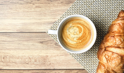 Perfect breakfast of croissant and coffee with milk on wooden table. Rustic style. Top view.