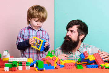 Bearded father and boy play together. Dad and kid build of plastic blocks. Useful toy. Child care development and upbringing. Father son game. Father and son create colorful constructions with bricks