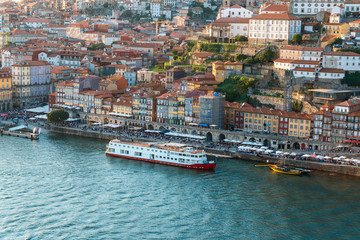 Fototapeta na wymiar tourist ship on the Douro River and picturesque houses on the embankment of the Portuguese city of Porto