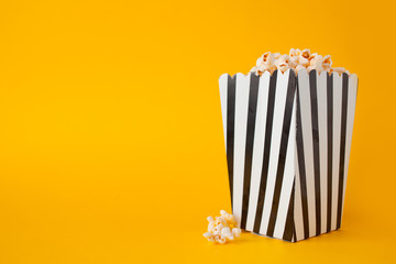 Popcorn in paper bag stand on yellow background side view