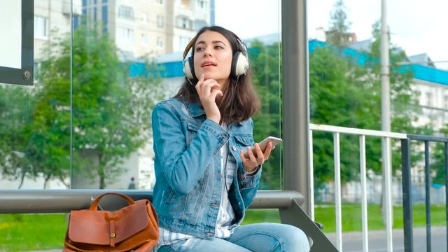 Girl listening to music at the modern bus stop