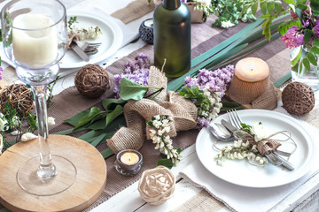 Beautifully elegant decorated table for holiday - wedding or valentine day with modern cutlery, bow, glass, candle and gift
