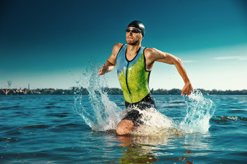 Professional triathlete swimming in river's open water. Man wearing swim equipment practicing triathlon on the beach in summer's day. Concept of healthy lifestyle, sport, action, motion and movement.