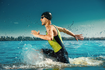 Professional triathlete swimming in river's open water. Man wearing swim equipment practicing...
