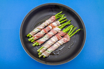 Tasty bacon wrapped asparagus in frying pan