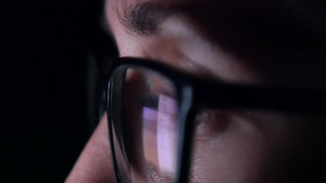 Extreme close up of woman's eye as she scrolls through her social media feed late at night.