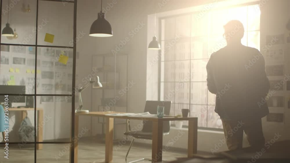 Poster young creative developer enters his studio, starts working on laptop at his desk. notebook screen sh