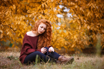 portrait of a beautiful young red-haired woman on the background of autumn landscape