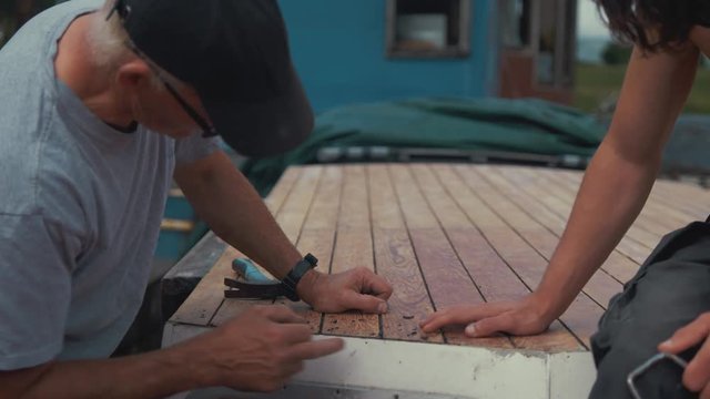 Father and son surveying cabin roof of wooden boat before undertaking maintenance.