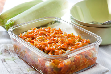 Squash stew with carrot and tomatoes in a square glass dish