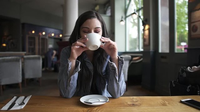 Beautiful Hispanic latina brunette sitting at the table having a coffee