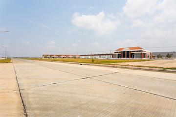 Fototapeta na wymiar empty road with green field in front of warehouse buildings