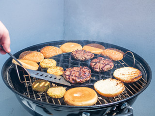 Gartengrill mit Fleischburger und Brötchen, Männerhand, Sommer, grillen