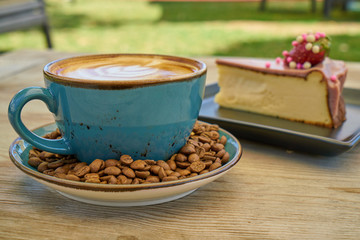 Latte coffee, coffee beans and cheesecake on the wooden table