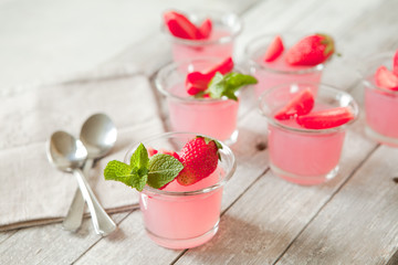 Berry portion jelly in glasses garnished with fresh strawberry and mint. Summer vegan dessert with agar-agar