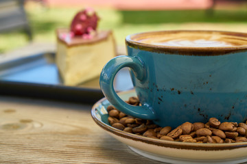Latte coffee, coffee beans and cheesecake on the wooden table