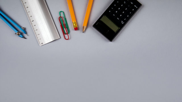Minimal work space, flat lay photo of workspace desk. Top view office desk with pencil, circus and calculator on gray color background. Panoramic banner background with copy space