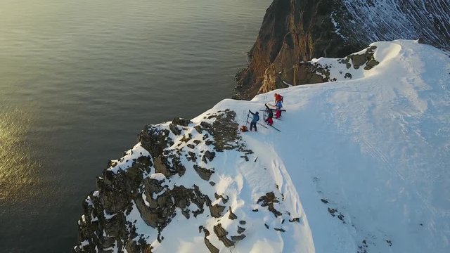 Drone circling around Freeriders preparing their skis to ride down in stunning Norwegian landscape.