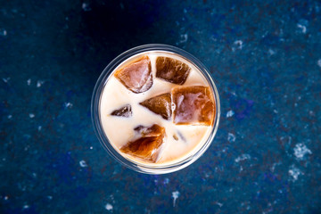 Cold summer refreshing drink with coffee ice and milk on a blue table