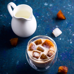 Cold summer refreshing drink with coffee ice and milk on a blue table