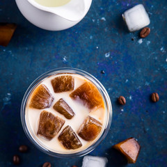 Cold summer refreshing drink with coffee ice and milk on a blue table