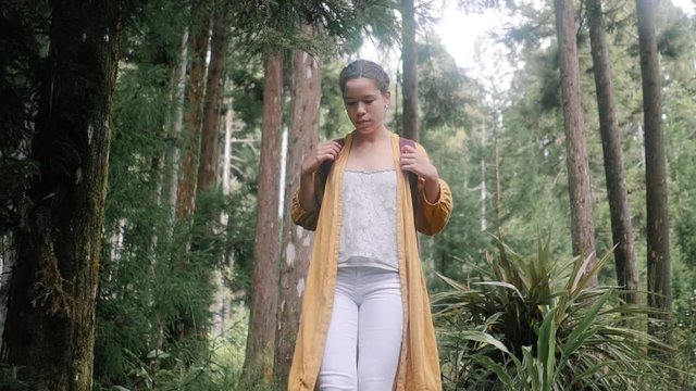 Tracking shot of a girl walking on a log, in the forest, on Reunion island, overseas department and region of France