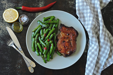 Green pea pods and pork steak on a plate. Balanced nutrition concept. Keto diet. Paleo diet. Pegan Diet.