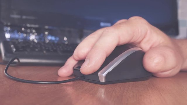 A man with disabilities working at the computer. The man has no fingers on his hand.