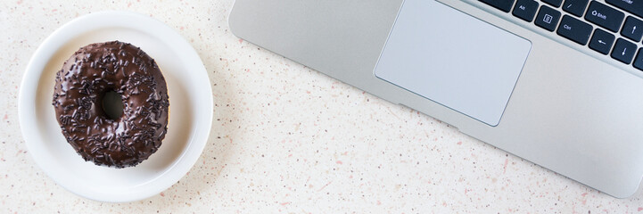 top of desk witk laptop keyboard and plate with donut panorama