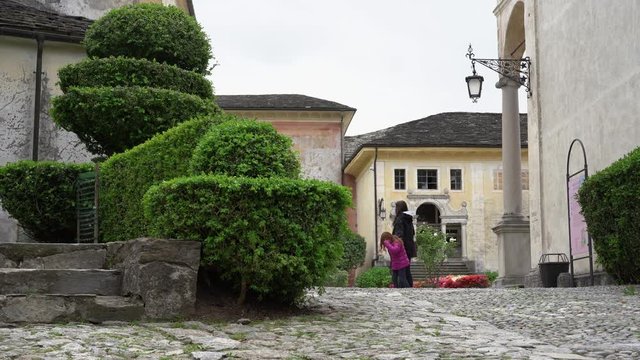 A mother and her little daughter carrying a teddy bear visiting the sacred mountain of Varallo christian devotional complex, a unesco world heritage site near the town of Varallo Sesia in Italy