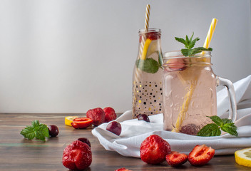 Refreshments on a hot summer day made from strawberries, mint and lemon with a sweet cherry on a white background