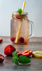 Cool cocktails of strawberry, mint and lemon in a glass dish in the background on a white background. Fruits in the foreground