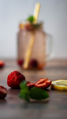 Cool cocktails of strawberry, mint and lemon in a glass dish in the background on a white background. Fruits in the foreground