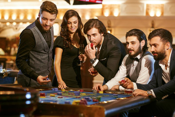 Group of friends playin groulette poker at a casino.