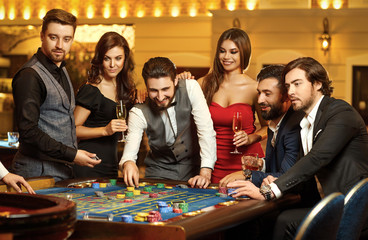 Friends make bets gambiling at the roulette table in the casino.