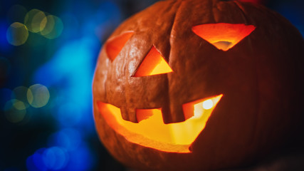 Halloween Still Life Colorful Theme: Close-up Shot of a Burning Pumpkin Lamp. In the Background Scary Blue Bokeh.