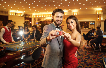 Beautiful glamour couple against the background of casino poker roulette.