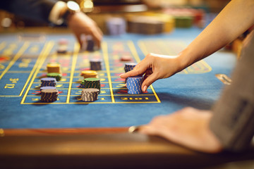 Hands with chips at poker roulette table gambling in a casino.