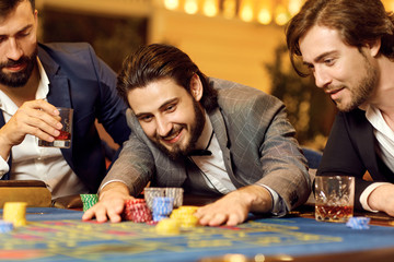 Group man in a suit at table roulette playing poker at a casino.