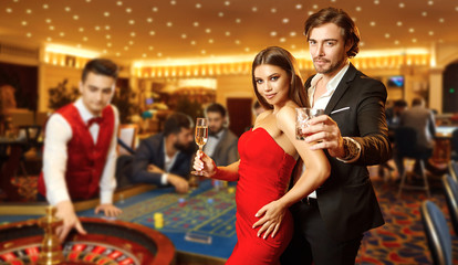 Beautiful glamour couple against the background of casino poker roulette.